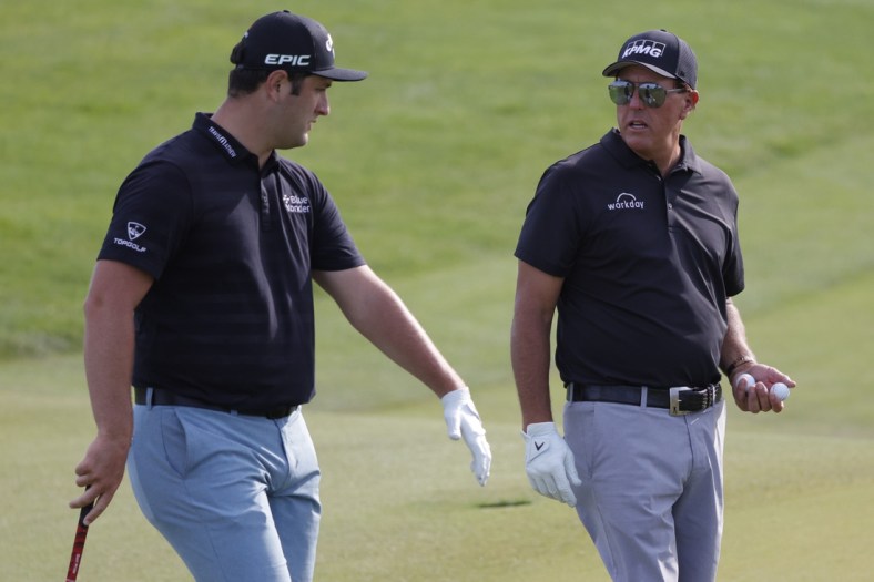May 17, 2021; Kiawah Island, South Carolina, USA; Jon Rahm (L) and Phil Mickelson (R) talk on the sixteenth green during a practice round for the PGA Championship golf tournament at Ocean Course at Kiawah Island Resort. Mandatory Credit: Geoff Burke-USA TODAY Sports
