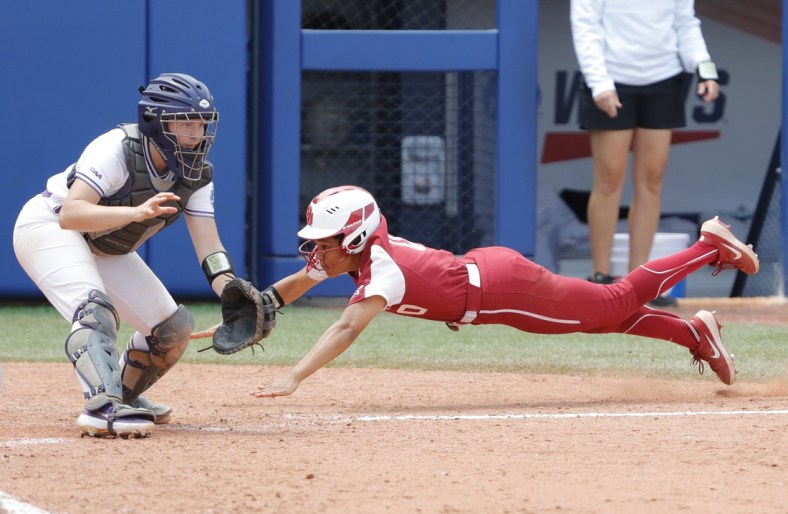 Jun 6, 2021; Oklahoma City, Oklahoma, USA;  Oklahoma s Rylie Boone (0) slides in at home past James Madison catcher Lauren Bernett (22) to score a run in the sixth inning during a Women s College World Series semi finals game at USA Softball Hall of Fame Stadium. Oklahoma won 6-3. Mandatory Credit: Alonzo Adams-USA TODAY Sports