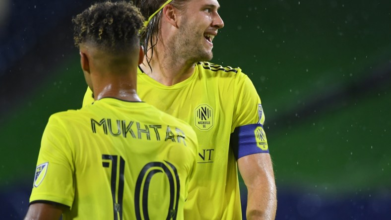 Aug 18, 2021; Nashville, TN, USA; Nashville SC defender Walker Zimmerman (25) and Nashville SC midfielder Hany Mukhtar (10) celebrate after a goal by Nashville SC forward C.J. Sapong (not pictured) during the first half against the Orlando City at Nissan Stadium. Mandatory Credit: Christopher Hanewinckel-USA TODAY Sports