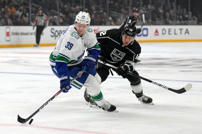 Dec 30, 2021; Los Angeles, California, USA; Vancouver Canucks right wing Alex Chiasson (39) and LA Kings center Trevor Moore (12) battle for the puck in the third period at Crypto.com Arena. Mandatory Credit: Kirby Lee-USA TODAY Sports