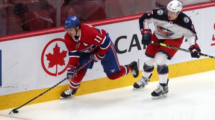 Feb 12, 2022; Montreal, Quebec, CAN; Montreal Canadiens right wing Brendan Gallagher (11) plays the puck against Columbus Blue Jackets defenseman Gavin Bayreuther (5) during the third period at Bell Centre. Mandatory Credit: Jean-Yves Ahern-USA TODAY Sports