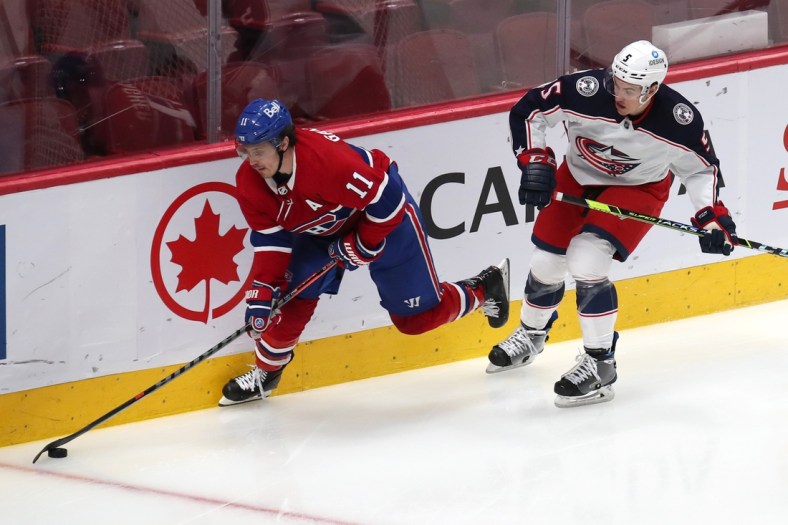 Feb 12, 2022; Montreal, Quebec, CAN; Montreal Canadiens right wing Brendan Gallagher (11) plays the puck against Columbus Blue Jackets defenseman Gavin Bayreuther (5) during the third period at Bell Centre. Mandatory Credit: Jean-Yves Ahern-USA TODAY Sports