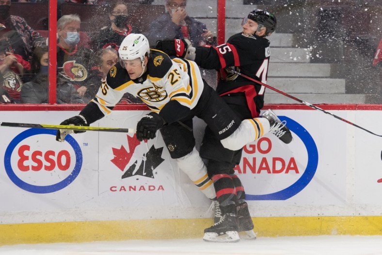 Feb 19, 2022; Ottawa, Ontario, CAN; Boston Bruins defenseman Brandon Carlo (25) is checked by Ottawa Senators left wing Parker Kelly (45) in the second period at the Canadian Tire Centre. Mandatory Credit: Marc DesRosiers-USA TODAY Sports