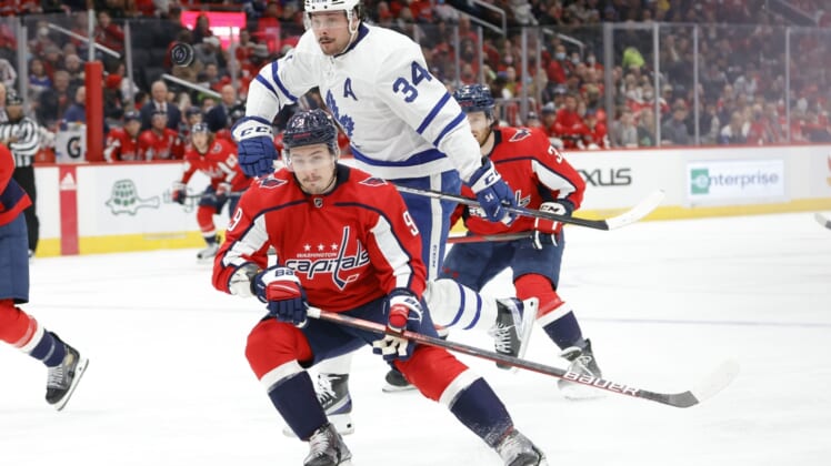 Feb 28, 2022; Washington, District of Columbia, USA; Toronto Maple Leafs center Auston Matthews (34) leaps around the check of Washington Capitals defenseman Dmitry Orlov (9) while chasing the puck in the second period at Capital One Arena. Mandatory Credit: Geoff Burke-USA TODAY Sports