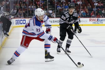 Mar 22, 2022; Newark, New Jersey, USA; New York Rangers defenseman Adam Fox (23) skates with the puck past New Jersey Devils center Jack Hughes (86) during the third period at Prudential Center. Mandatory Credit: Tom Horak-USA TODAY Sports