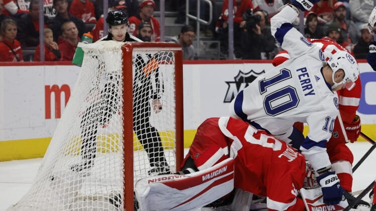 Mar 26, 2022; Detroit, Michigan, USA;  Tampa Bay Lightning right wing Corey Perry (10) falls on Detroit Red Wings goaltender Alex Nedeljkovic (39) in the third period at Little Caesars Arena. Mandatory Credit: Rick Osentoski-USA TODAY Sports