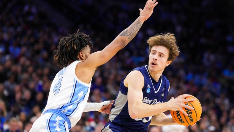 Mar 27, 2022; Philadelphia, PA, USA; St. Peters Peacocks guard Doug Edert (25) controls the ball as North Carolina Tar Heels guard R.J. Davis (4) defends during the first half in the finals of the East regional of the men's college basketball NCAA Tournament at Wells Fargo Center. Mandatory Credit: Mitchell Leff-USA TODAY Sports