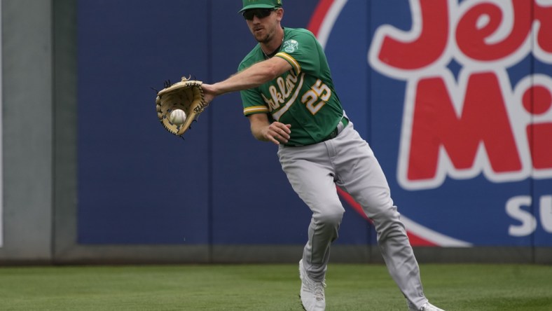 Mar 28, 2022; Tempe, Arizona, USA; Oakland Athletics right fielder Stephen Piscotty (25) fields the ball against the Los Angeles Angels during a spring training game at Tempe Diablo Stadium. Mandatory Credit: Rick Scuteri-USA TODAY Sports