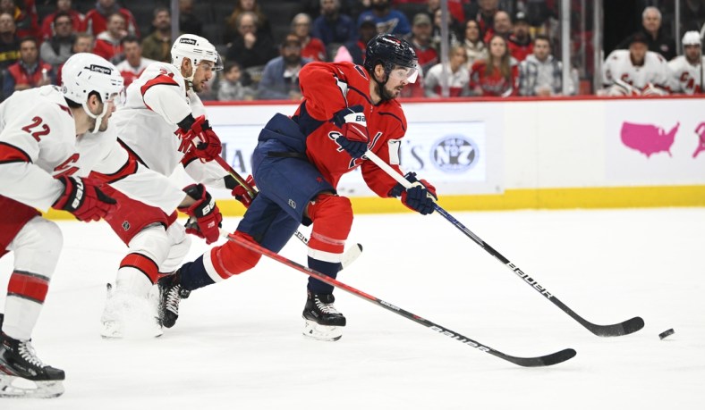 Mar 28, 2022; Washington, District of Columbia, USA; Washington Capitals left wing Marcus Johansson (90) carries the puck past Carolina Hurricanes defenseman Brett Pesce (22) during the first period at Capital One Arena. Mandatory Credit: Brad Mills-USA TODAY Sports