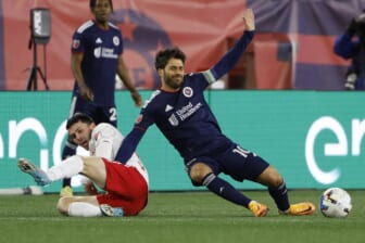 Apr 2, 2022; Foxborough, Massachusetts, USA; New England Revolution midfielder Carles Gil (10) is taken down by New York Red Bulls midfielder Lewis Morgan (10) during the first half at Gillette Stadium. Mandatory Credit: Winslow Townson-USA TODAY Sports