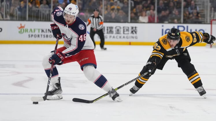 Apr 2, 2022; Boston, Massachusetts, USA; Columbus Blue Jackets defenseman Dean Kukan (46) skates with the puck against Boston Bruins left wing Brad Marchand (63) during the first period at TD Garden. Mandatory Credit: Gregory Fisher-USA TODAY Sports