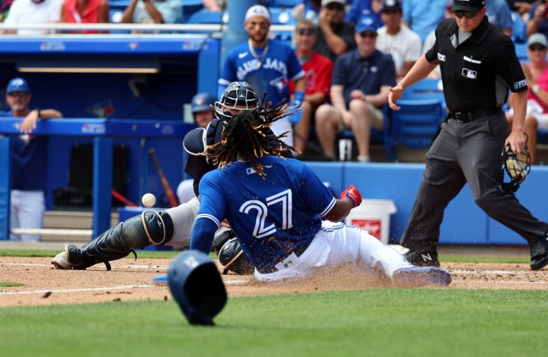 Apr 3, 2022; Dunedin, Florida, USA; Toronto Blue Jays first baseman Vladimir Guerrero Jr. (27) slides safe into home plate ahead of the throw to New York Yankees catcher Max McDowell (98) during the first inning during spring training at TD Ballpark. Mandatory Credit: Kim Klement-USA TODAY Sports