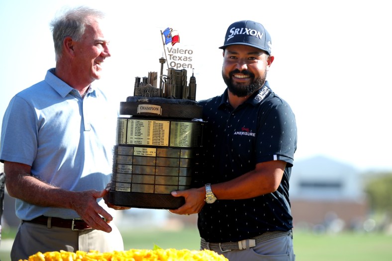 Apr 3, 2022; San Antonio, Texas, USA; J.J. Spaun (right) poses with a tournament official while holding the champion's trophy after winning Valero Texas Open golf tournament. Mandatory Credit: Erik Williams-USA TODAY Sports