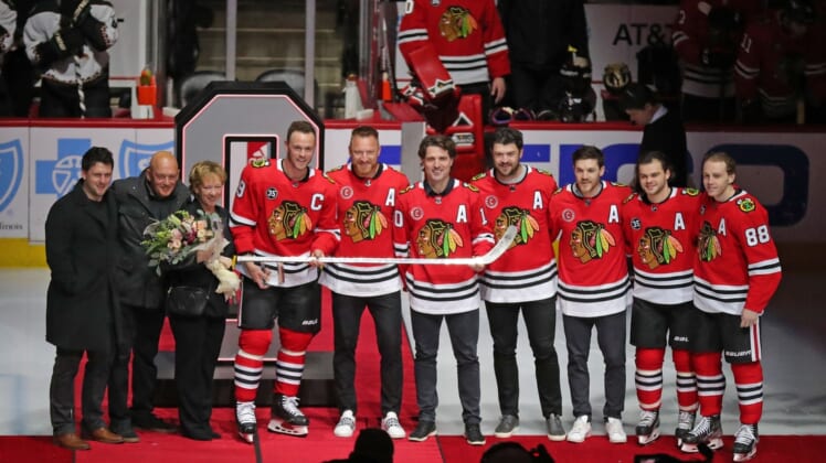 Apr 3, 2022; Chicago, Illinois, USA; Chicago Blackhawks center Jonathan Toews (19) is honored for his 1,000th NHL game, attended by his family, and current and former Blackhawks players (from left to right) Marian Hossa and Patrick Sharp and Brent Seabrook and Andrew Shaw and  left wing Alex DeBrincat (12) and right wing Patrick Kane (88) prior to the first period against the Arizona Coyotes at the United Center. Mandatory Credit: Dennis Wierzbicki-USA TODAY Sports