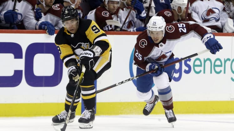 Apr 5, 2022; Pittsburgh, Pennsylvania, USA;  Pittsburgh Penguins center Evan Rodrigues (9) moves the puck against Colorado Avalanche right wing Logan O'Connor (25) during the first period at PPG Paints Arena. Mandatory Credit: Charles LeClaire-USA TODAY Sports