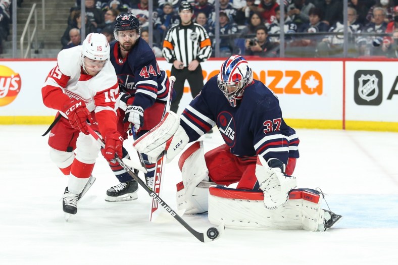 Apr 6, 2022; Winnipeg, Manitoba, CAN; Detroit Red Wings forward Jakub Vrana (15) chases the rebound in front of Winnipeg Jets goalie Connor Hellebuyck (37) during the first period  at Canada Life Centre. Mandatory Credit: Terrence Lee-USA TODAY Sports