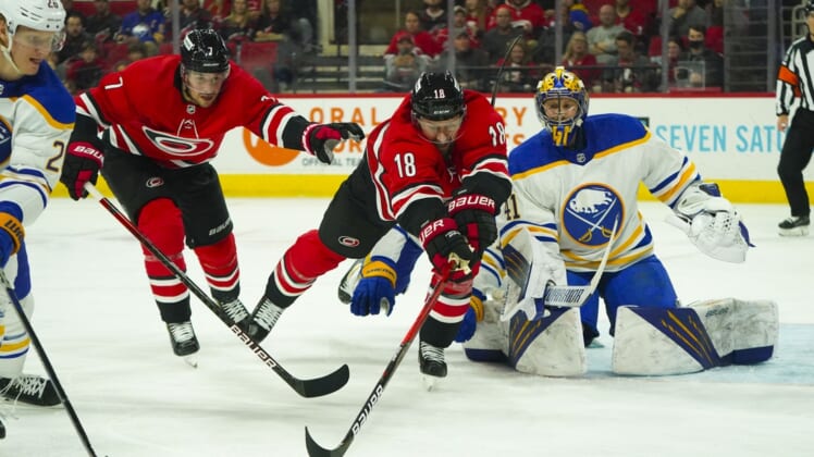 Apr 7, 2022; Raleigh, North Carolina, USA;  Carolina Hurricanes center Derek Stepan (18) and defenseman Brendan Smith (7) chase after the puck against Buffalo Sabres goaltender Craig Anderson (41) during the first period at PNC Arena. Mandatory Credit: James Guillory-USA TODAY Sports