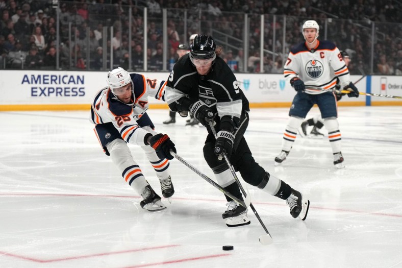 Apr 7, 2022; Los Angeles, California, USA; LA Kings center Adrian Kempe (9) and Edmonton Oilers defenseman Darnell Nurse (25) reach for the puck in the second period at Crypto.com Arena. Mandatory Credit: Kirby Lee-USA TODAY Sports