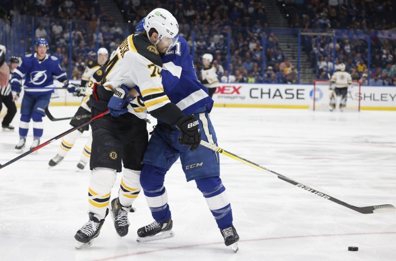 Apr 8, 2022; Tampa, Florida, USA;  Tampa Bay Lightning center Brayden Point (21) and Boston Bruins left wing Jake DeBrusk (74) fight for the loose puck during the first period at Amalie Arena. Mandatory Credit: Reinhold Matay-USA TODAY Sports