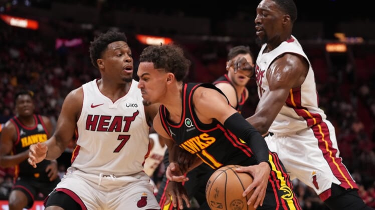 Apr 8, 2022; Miami, Florida, USA; Atlanta Hawks guard Trae Young (11) drives the ball around Miami Heat guard Kyle Lowry (7) and  center Bam Adebayo (13) during the first half at FTX Arena. Mandatory Credit: Jasen Vinlove-USA TODAY Sports