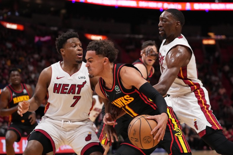 Apr 8, 2022; Miami, Florida, USA; Atlanta Hawks guard Trae Young (11) drives the ball around Miami Heat guard Kyle Lowry (7) and  center Bam Adebayo (13) during the first half at FTX Arena. Mandatory Credit: Jasen Vinlove-USA TODAY Sports