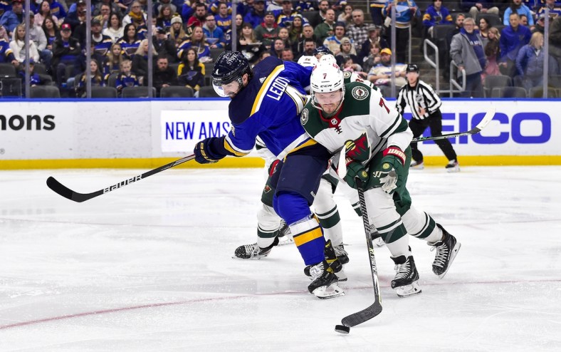 Apr 8, 2022; St. Louis, Missouri, USA;  St. Louis Blues defenseman Nick Leddy (4) and Minnesota Wild defenseman Dmitry Kulikov (7) battle for the puck during the second period at Enterprise Center. Mandatory Credit: Jeff Curry-USA TODAY Sports