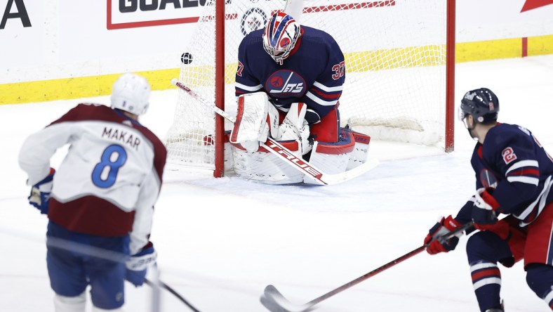 Apr 8, 2022; Winnipeg, Manitoba, CAN; Colorado Avalanche defenseman Cale Makar (8) scores on Winnipeg Jets goaltender Connor Hellebuyck (37) in overtime at Canada Life Centre. Mandatory Credit: James Carey Lauder-USA TODAY Sports