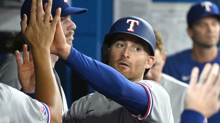 Apr 9, 2022; Toronto, Ontario, CAN;  Texas Rangers left fielder Brad Miller (13) is greeted in the dugout by team mates after scoring against the Toronto Blue Jays in the third inning at Rogers Centre. Mandatory Credit: Dan Hamilton-USA TODAY Sports
