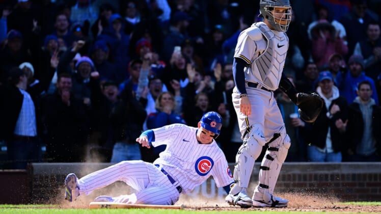 Apr 9, 2022; Chicago, Illinois, USA; Chicago Cubs first baseman Frank Schwindel (18) slides at home plate to score in the sixth inning against Milwaukee Brewers catcher Victor Caratini (7) at Wrigley Field. Mandatory Credit: Quinn Harris-USA TODAY Sports
