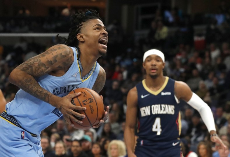 Apr 9, 2022; Memphis, Tennessee, USA; Memphis Grizzlies guard Ja Morant (12) goes for a lay-up while New Orleans Pelicans guard Devonte' Graham (4) looks on during the first half at FedExForum. Mandatory Credit: Christine Tannous-USA TODAY Sports