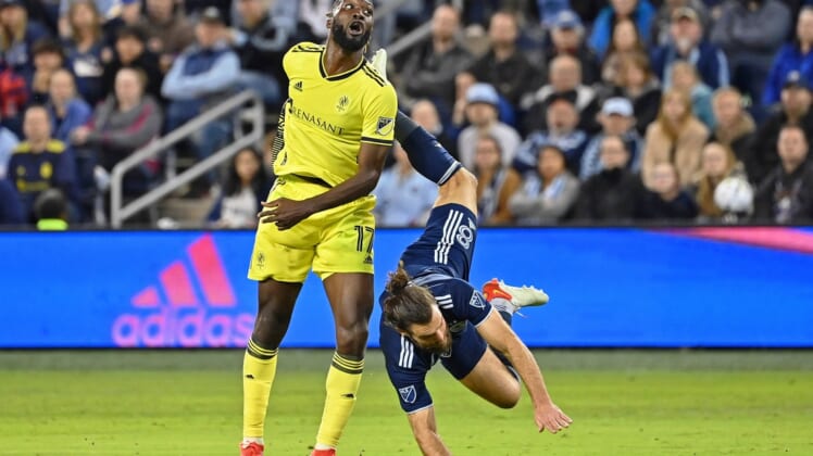 Apr 9, 2022; Kansas City, Kansas, USA; Sporting Kansas City defender Graham Zusi (8) is upended after making a play for the ball against Nashville SC forward C.J. Sapong (17) during the first half at Children's Mercy Park. Mandatory Credit: Peter Aiken-USA TODAY Sports