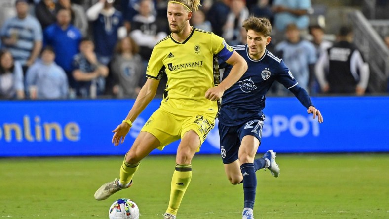 Apr 9, 2022; Kansas City, Kansas, USA; Nashville SC defender Walker Zimmerman (25) passes the ball while defended by Sporting Kansas City midfielder Marinos Tzionis (27) during the second half at Children's Mercy Park. Mandatory Credit: Peter Aiken-USA TODAY Sports