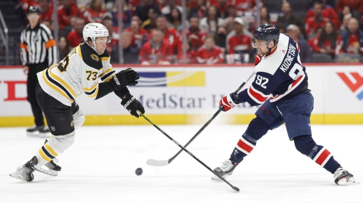 Apr 10, 2022; Washington, District of Columbia, USA; Washington Capitals center Evgeny Kuznetsov (92) shoots the puck as Boston Bruins defenseman Charlie McAvoy (73) defends in the first period at Capital One Arena. Mandatory Credit: Geoff Burke-USA TODAY Sports