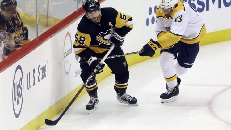 Apr 10, 2022; Pittsburgh, Pennsylvania, USA;  Pittsburgh Penguins defenseman Kris Letang (58) moves the puck against Nashville Predators center Yakov Trenin (13) during the second period at PPG Paints Arena. Mandatory Credit: Charles LeClaire-USA TODAY Sports