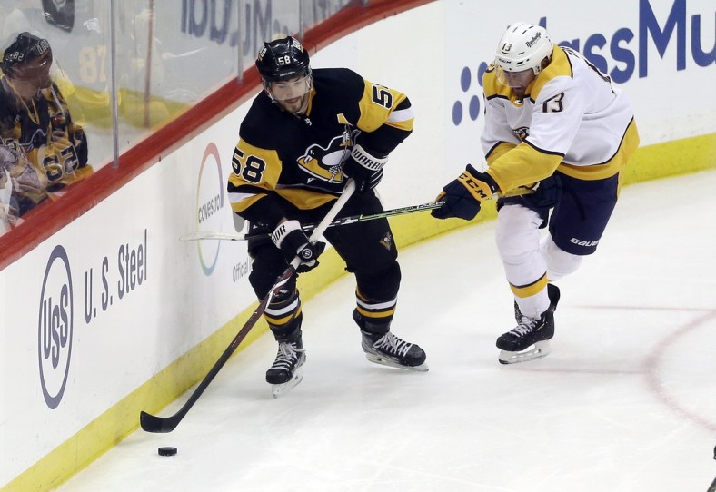 Apr 10, 2022; Pittsburgh, Pennsylvania, USA;  Pittsburgh Penguins defenseman Kris Letang (58) moves the puck against Nashville Predators center Yakov Trenin (13) during the second period at PPG Paints Arena. Mandatory Credit: Charles LeClaire-USA TODAY Sports