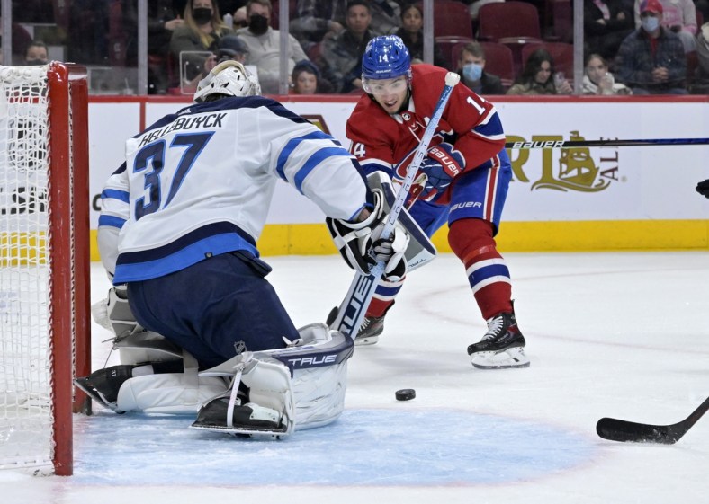 Apr 11, 2022; Montreal, Quebec, CAN; Winnipeg Jets goalie Connor Hellebuyck (37) stops Montreal Canadiens forward Nick Suzuki (14) during the first period at the Bell Centre. Mandatory Credit: Eric Bolte-USA TODAY Sports