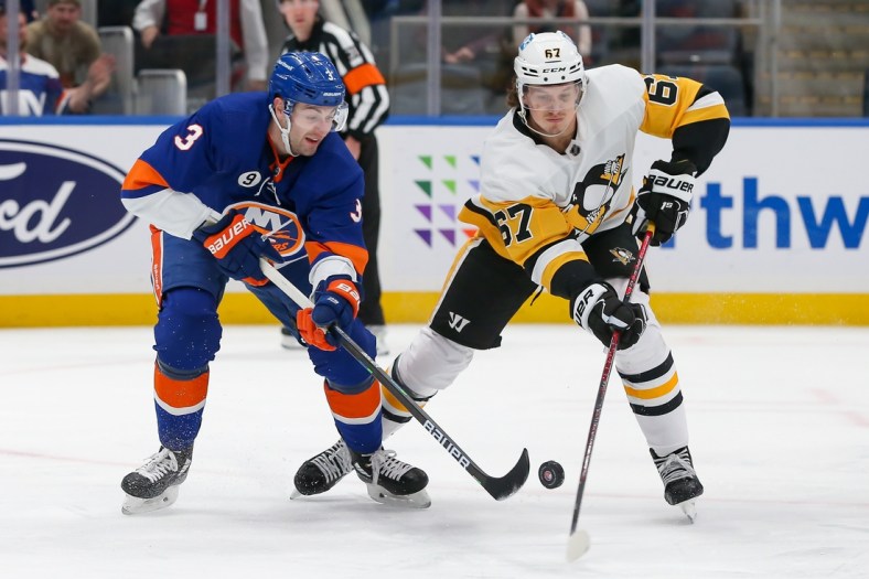 Apr 12, 2022; Elmont, New York, USA; New York Islanders defenseman Adam Pelech (3) and Pittsburgh Penguins right wing Rickard Rakell (67) battle for the puck during the first period at UBS Arena. Mandatory Credit: Tom Horak-USA TODAY Sports