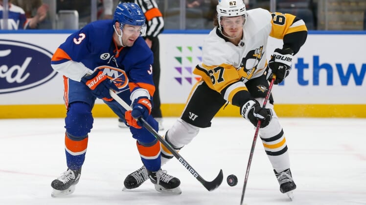 Apr 12, 2022; Elmont, New York, USA; New York Islanders defenseman Adam Pelech (3) and Pittsburgh Penguins right wing Rickard Rakell (67) battle for the puck during the first period at UBS Arena. Mandatory Credit: Tom Horak-USA TODAY Sports