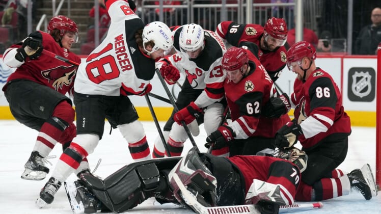Apr 12, 2022; Glendale, Arizona, USA; New Jersey Devils and Arizona Coyotes players go after a loose puck around Arizona Coyotes goaltender Karel Vejmelka (70) during the first period at Gila River Arena. Mandatory Credit: Joe Camporeale-USA TODAY Sports