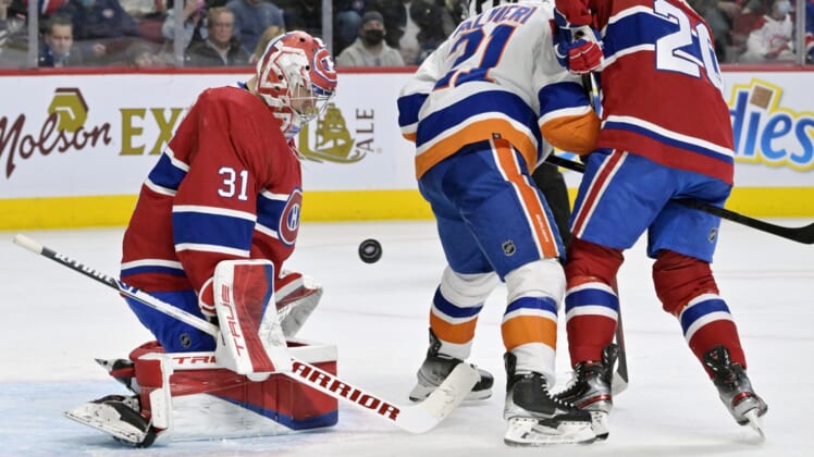 Apr 15, 2022; Montreal, Quebec, CAN; Montreal Canadiens goalie Carey Price (31) makes a save behind the screen of New York Islanders forward Kyle Palmieri (21) and teammate defenseman Chris Wideman (20) during the first period at the Bell Centre. Mandatory Credit: Eric Bolte-USA TODAY Sports