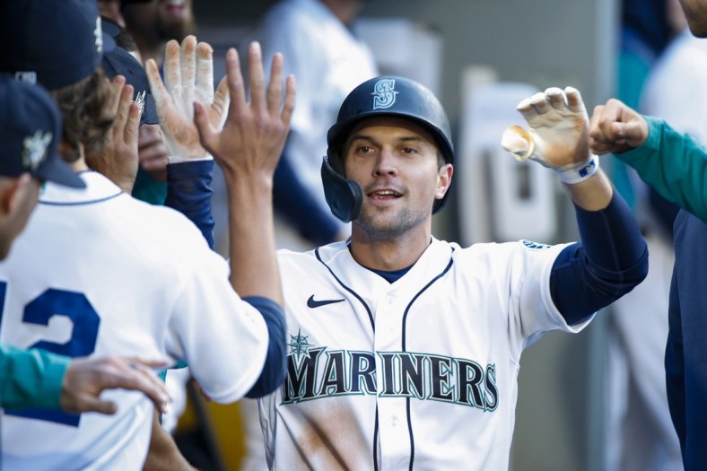 Apr 15, 2022; Seattle, Washington, USA; Seattle Mariners second baseman Adam Frazier (42) is greeted by teammates in the dugout after scoring a run against the Houston Astros during the first inning at T-Mobile Park. Mandatory Credit: Joe Nicholson-USA TODAY Sports
