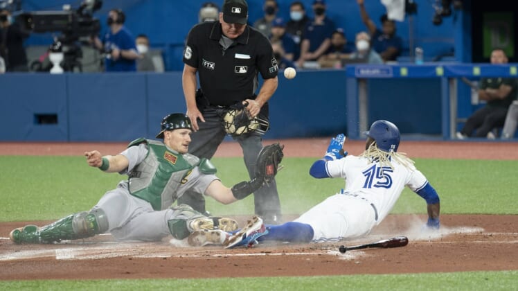 Apr 16, 2022; Toronto, Ontario, CAN; Toronto Blue Jays left fielder Raimel Tapia (15) slides into him plate safe ahead of the tag from Oakland Athletics catcher Sean Murphy (12) during the first inning at Rogers Centre. Mandatory Credit: Nick Turchiaro-USA TODAY Sports