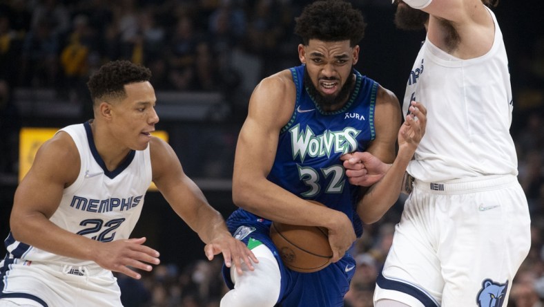 Apr 16, 2022; Memphis, Tennessee, USA; Minnesota Timberwolves center Karl-Anthony Towns (32) keeps control of the ball as he   s guarded by Memphis Grizzlies guard Desmond Bane (22) and Memphis Grizzlies center Steven Adams (4) during the first half of game one of the first round for the 2022 NBA playoffs at FedExForum. Mandatory Credit: Christine Tannous-USA TODAY Sports