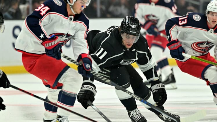 Apr 16, 2022; Los Angeles, California, USA;  Los Angeles Kings center Anze Kopitar (11) moves the puck away from Columbus Blue Jackets center Cole Sillinger (34) in the first period of the game at Crypto.com Arena. Mandatory Credit: Jayne Kamin-Oncea-USA TODAY Sports