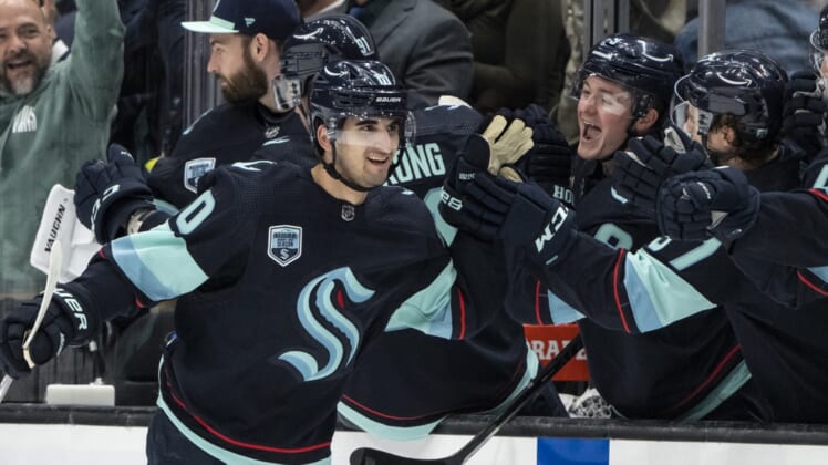 Apr 16, 2022; Seattle, Washington, USA; Seattle Kraken forward Matty Beniers (10) is congratulated by teammates on the bench after scoring his first NHL during the second period against the New Jersey Devils at Climate Pledge Arena. Mandatory Credit: Stephen Brashear-USA TODAY Sports