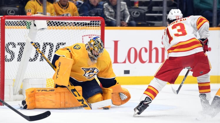 Apr 19, 2022; Nashville, Tennessee, USA; Nashville Predators goaltender Juuse Saros (74) makes a save on a shot attempt by Calgary Flames left wing Johnny Gaudreau (13) during the first period at Bridgestone Arena. Mandatory Credit: Christopher Hanewinckel-USA TODAY Sports