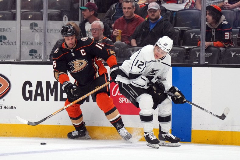 Apr 19, 2022; Anaheim, California, USA; Anaheim Ducks center Ryan Getzlaf (15) and LA Kings center Trevor Moore (12) battle for the puck in the first period at Honda Center. Mandatory Credit: Kirby Lee-USA TODAY Sports