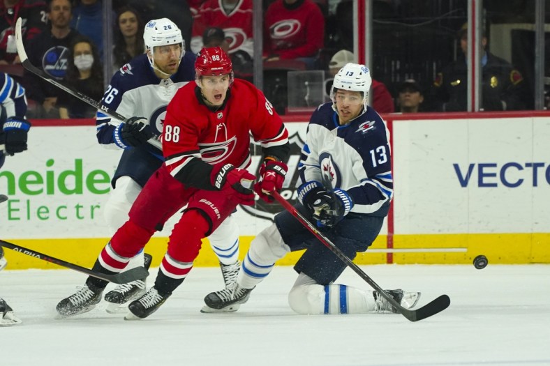 Apr 21, 2022; Raleigh, North Carolina, USA;  Carolina Hurricanes center Martin Necas (88) and Winnipeg Jets left wing Zach Sanford (13) watch the puck during the first period at PNC Arena. Mandatory Credit: James Guillory-USA TODAY Sports