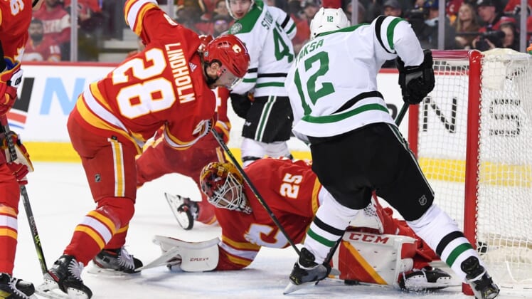 Apr 21, 2022; Calgary, Alberta, CAN; Calgary Flames forward Elias Lindholm (28) and goalie Jacob Markstrom (25) try and stop a shot from Dallas Stars forward Radek Faksa (12) during the second period at Scotiabank Saddledome. Mandatory Credit: Candice Ward-USA TODAY Sports