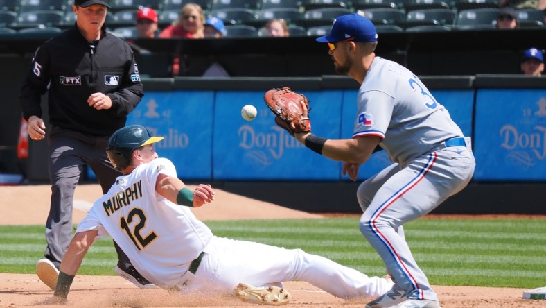 Apr 24, 2022; Oakland, California, USA; Oakland Athletics catcher Sean Murphy (12) dives safely back to first base against Texas Rangers first baseman Nathanial Lowe (30) during the fourth inning at RingCentral Coliseum. Mandatory Credit: Kelley L Cox-USA TODAY Sports